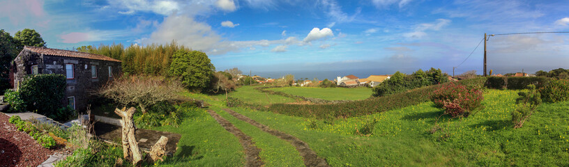 Fototapeta na wymiar Panoramic view with meadow and lava stone house at the island of Pico, Azores islands, Portugal