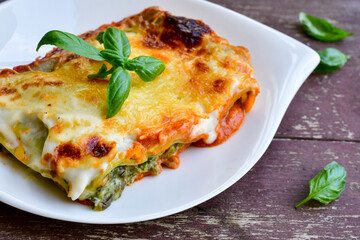   Delicious Home made Lasagna  with minced meat,tomato sauce and spinach  on a wooden rustic  background.Home made italian meal