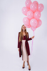 stylish young girl in burgundy clothes and pink balloons on a white background