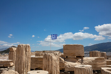 Athens, Greece. Greek flag and ancient column remains in Acropolis against blue sky background