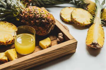 Fototapeta na wymiar fresh pineapple juice and cut delicious fruit on wooden tray on white background