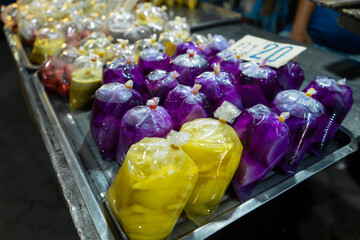 Colored desserts in plastic bags at a street food market in Asia. Unusual Asian food.