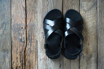 New leather men's sandals on the wooden floor. Top view. Copy space.