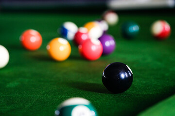 Man's hand and Cue arm playing snooker game or preparing aiming to shoot pool balls on a green billiard table. Colorful snooker balls on green frieze.