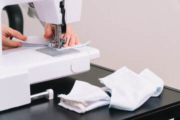 Woman sews a protective mask. Making cotton fabric medical mask, coronavirus protection. Quarantine lesson