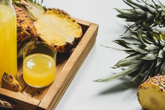 Fresh Pineapple Juice And Cut Delicious Fruit On Wooden Tray On White Background