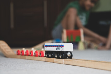 School age children building a wooden toy train track at home on the carpet. 