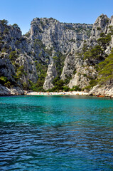 People relaxing on a white beach and in the turquoise waters of a calanque near Marseille in the Mediterranean Sea.