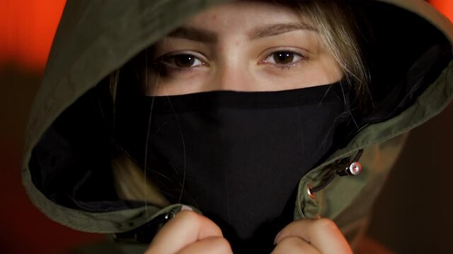Sad female protester in black face mask and hood during Black Lives Matter meeting