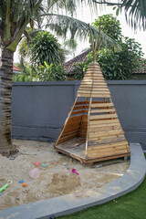 Outdoor children playground. Wooden teepee playhouse on sand.