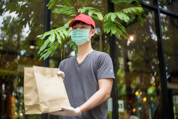 An Asian delivery man is wearing face mask, holding grocery bag , Safety home delivery concept