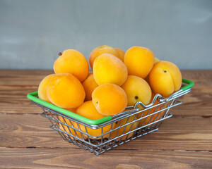 Ripe apricots in a metal basket standing on a wooden table,