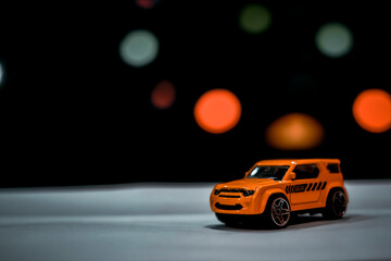 Orange toy car with black bokeh background
