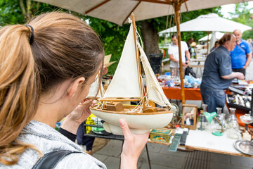 Attractive woman looking at toy model sail boat and dreaming.