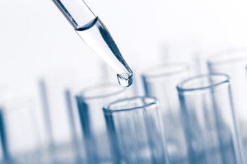 pipette with a drop and scientific laboratory test tubes in a research laboratory.