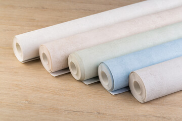 rolls of multi-colored paper wallpaper on a wooden table
