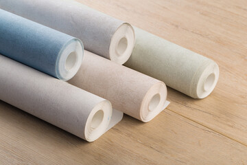 rolls of multi-colored paper wallpaper on a wooden table