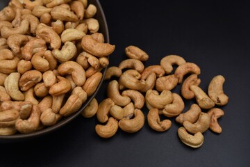 Roasted cashews in brown cups on a black background