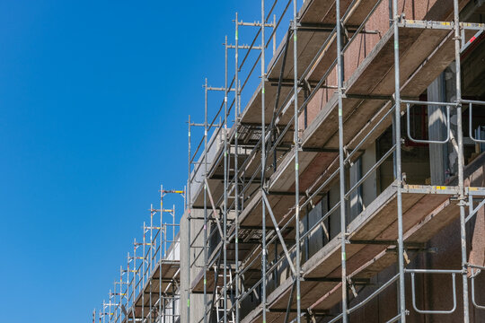 Konzept Baustelle: Die Fassade eines gro&szlig;en Geb&auml;udes ist komplett einger&uuml;stet f&uuml;r die Sanierung und viel blauer Himmel &ndash; sehr viel Copyspace, selektiver Fokus 
