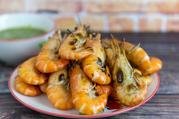 Grilled shrimp and a dipping sauce bowl placed on a plate