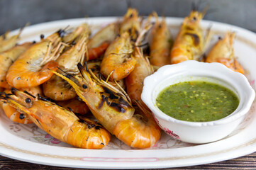 Grilled shrimp and a dipping sauce bowl placed on a plate