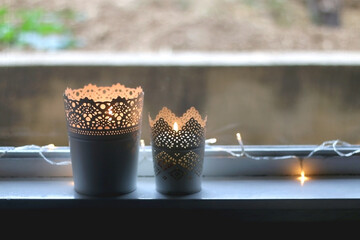 Two candle holders with lit candles and fairy lights. Home decor detail. Selective focus.