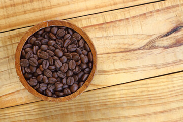 coffee beans in wooden bowl on wooden top table and copy space for text or design