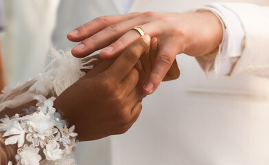 Obraz na płótnie Canvas bride black skin wears a ring on the hand of the groom white skin on wedding ceremony