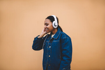 Charming dark skinned hipster girl checking sound in headphones connecting to smartphone