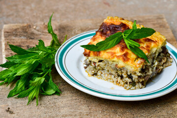 Casserole  with  rice and cheese pie with  lamb meat and mint .  Rustic background. 