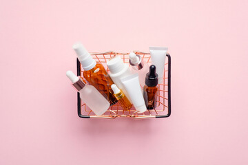 Shopping basket with natural organic cosmetics on pink background. Buying beauty products concept. Flat lay, top view.