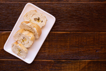 White dish with toasted bread on wooden background. Top view with copy space.
