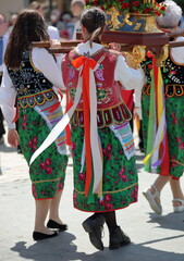 Girls in traditional folk costumes from Krakow region in Poland hold religious statue while join annual Corpus Christi procesion