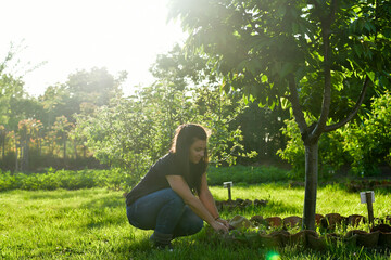 Smiling happy  young  woman gardener sitting in an  organic  orchar apple garden in a sunny day