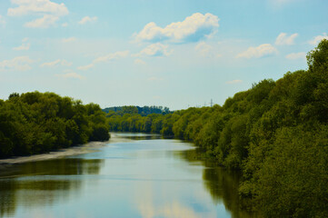 river, blue sky, white clouds and green trees. nature in summer.