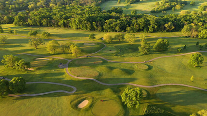 Aerial view of Golf course. Establishing shot, drone flying over golf club. Early morning, summertime, sunlight