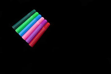 Set of markers of different colors on black background.