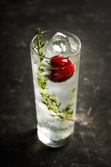 Gin based cocktail with cherries and thyme herbs on the rustic background. Selective focus. Shallow depth of field. 