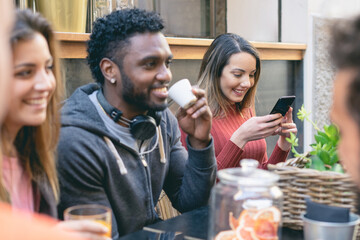 Interracial friends drinking coffee sitting at the table and having fun together. Interracial and trust relationship concept