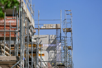 Konzept Baustelle: Die Fassade eines großen Gebäudes ist komplett eingerüstet für die Sanierung und viel blauer Himmel – sehr viel Copyspace, selektiver Fokus