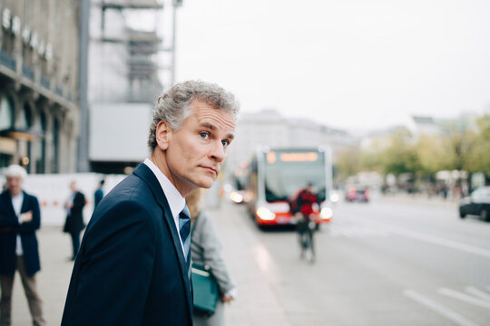 Mature businessman looking away while standing in city