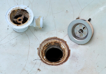 A dirty old rusty drain for a bath. Disassembled rusty bathtub drain. An old cracked broken bathtub.