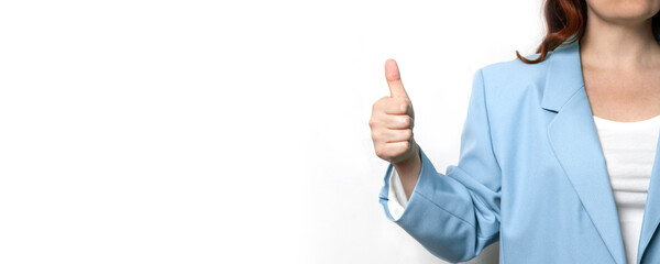 Young business woman in blue stylish jacket shows like or thumbs up on a gray wall background phone in the office.