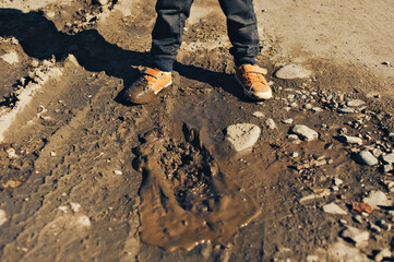 A child is walking and has stepped in a muddy puddle