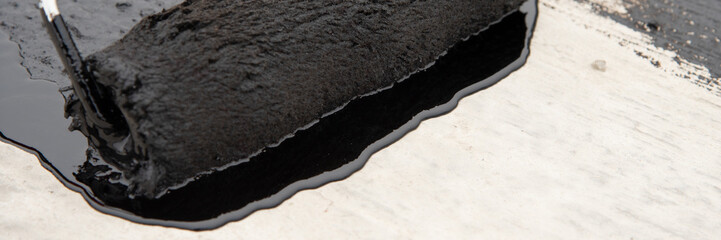 Worker applies bitumen mastic on the foundation