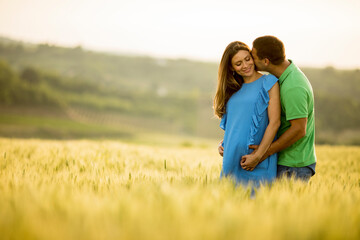 Young husband and his pregnant wife in the summer field