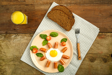 Scrambled eggs with sausages in the shape of a sun children's breakfast m glass of juice.