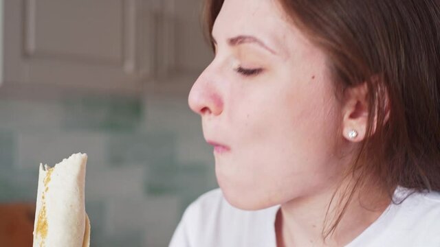 A woman eats roll, fast food. Shaurma in female hands. Girl bites kebab