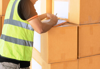 Warehouse worker writing on clipboard and checking order shipment boxes. warehouse inventory management.