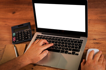Man's hands using laptop with blank screen on desk in home interior.